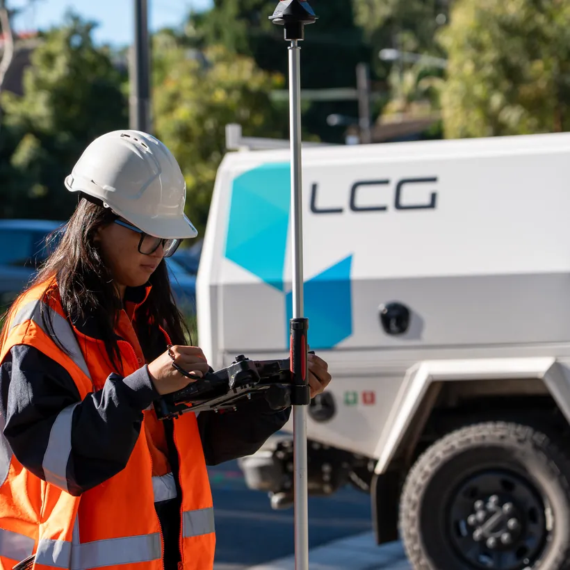 LCG surveyor with a GPS rover beside a branded LCG vehicle