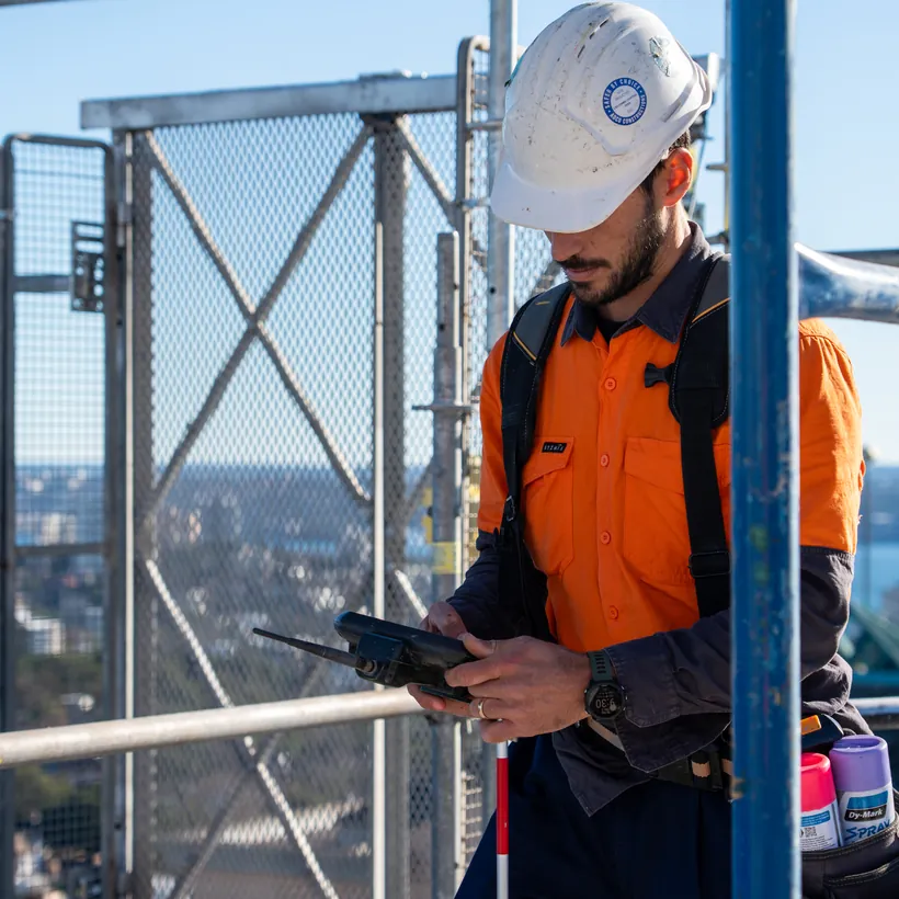 LCG surveyor with a data collector above the Sydney skyline