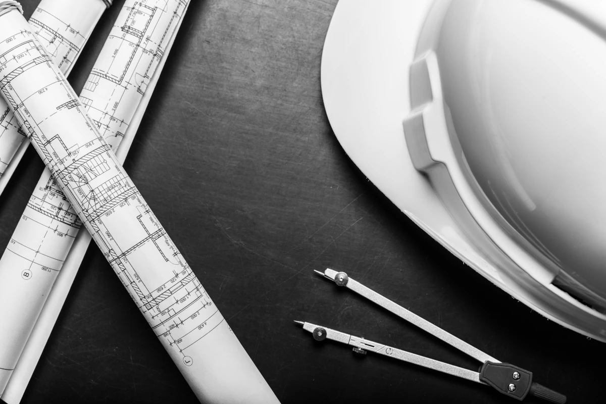 Architectural blueprints with drafting tools and a hard hat