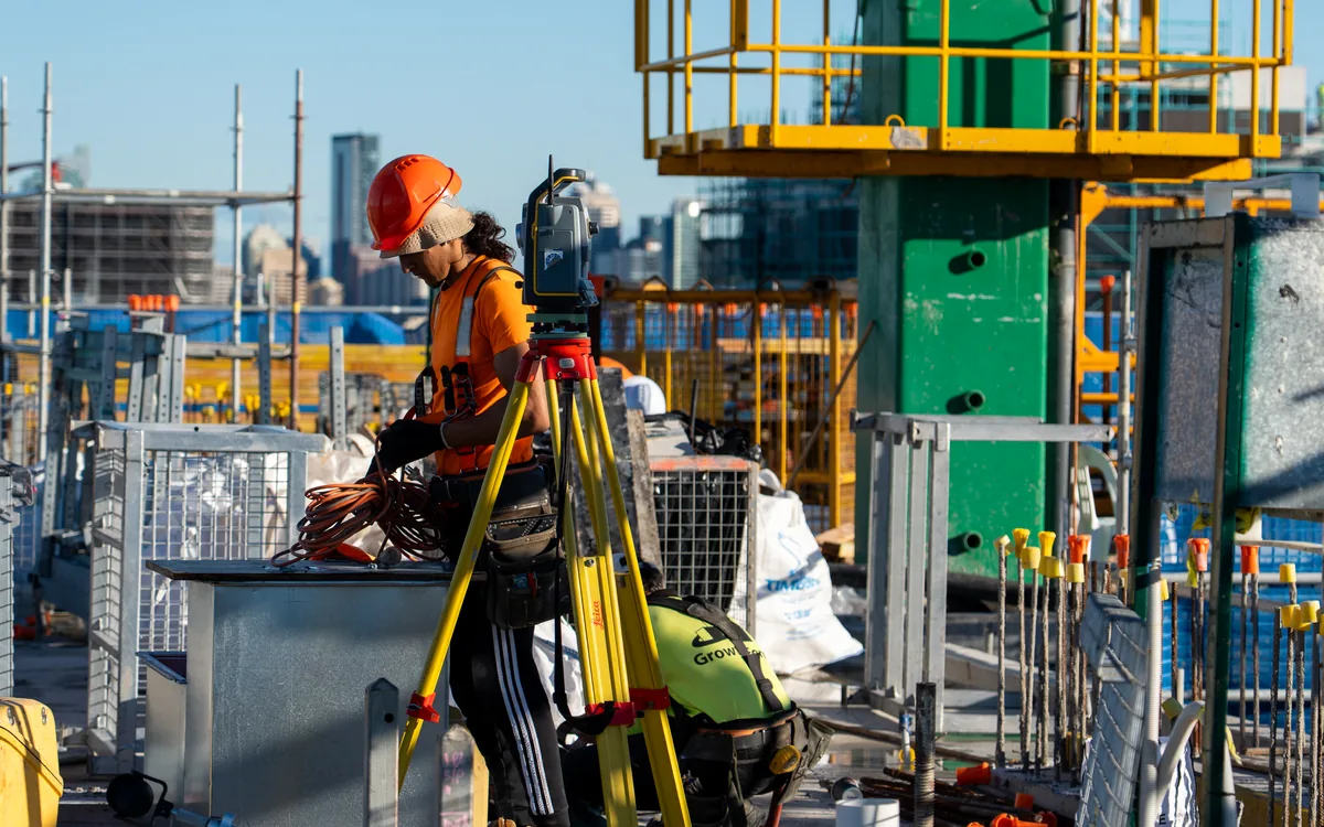 LCG surveyor at a total station on a formwork construction site with the city skyline behind
